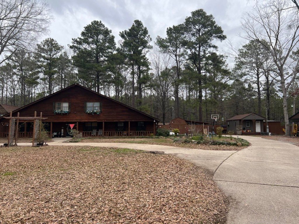 The real house — a brown wooden house with a wide porch under tall pines